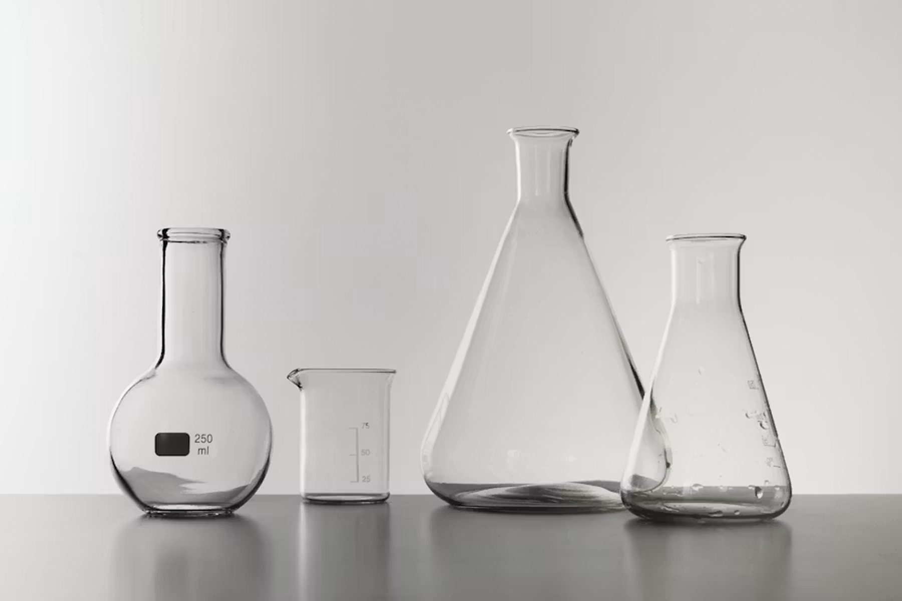 A row of laboratory flasks and a beaker on a clean surface